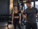 Mann trener biceps med enarms hantelcurl i et treningssenter.